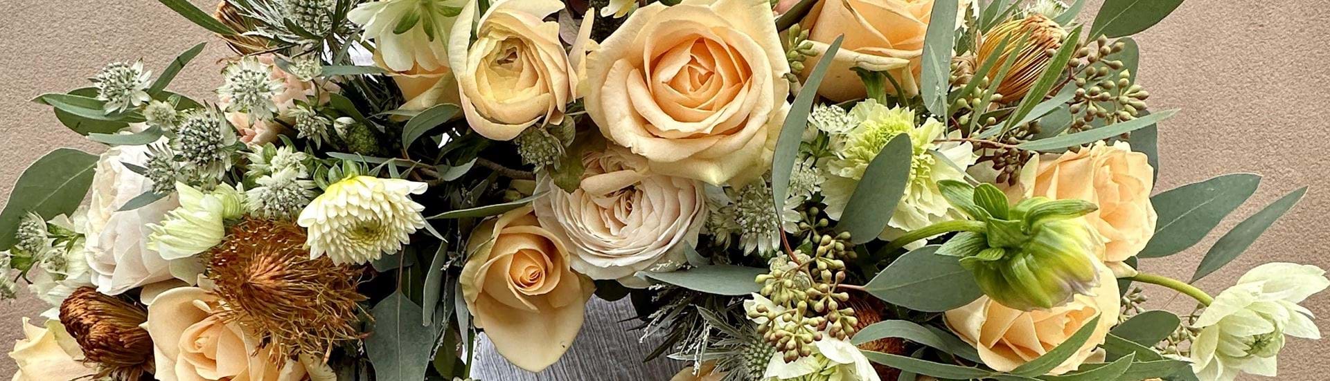 Begravelseskrans med store roser i creme nuancer.