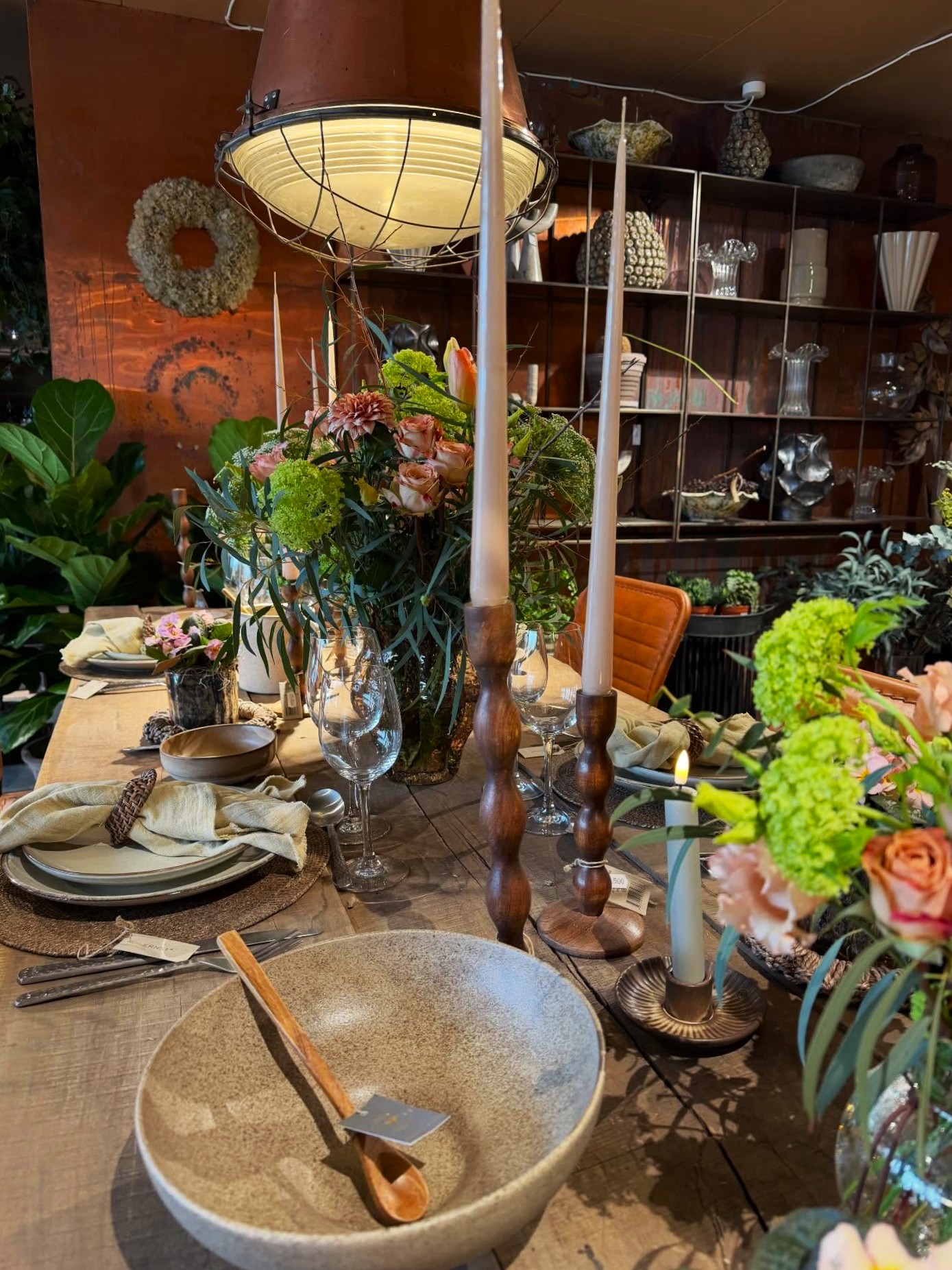 Rustikt plankebord pyntet op til med cremefarvet stentøj, små stager og vaser med snitblomster.  