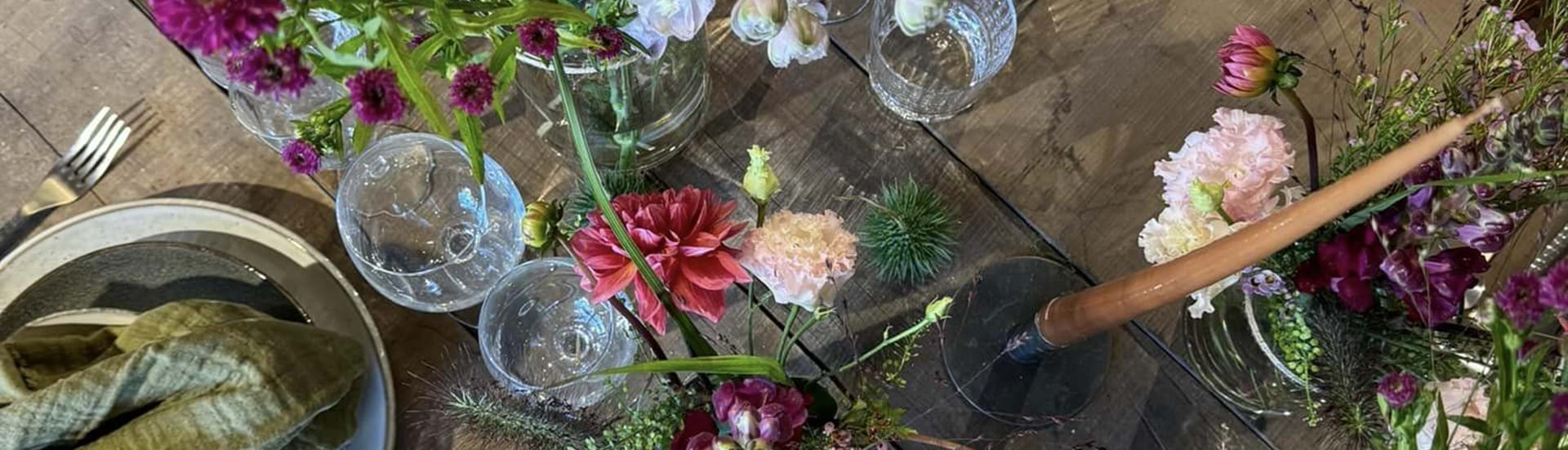 rustikt plankebord med cremefarvet vase og mixede afskårne blomster.