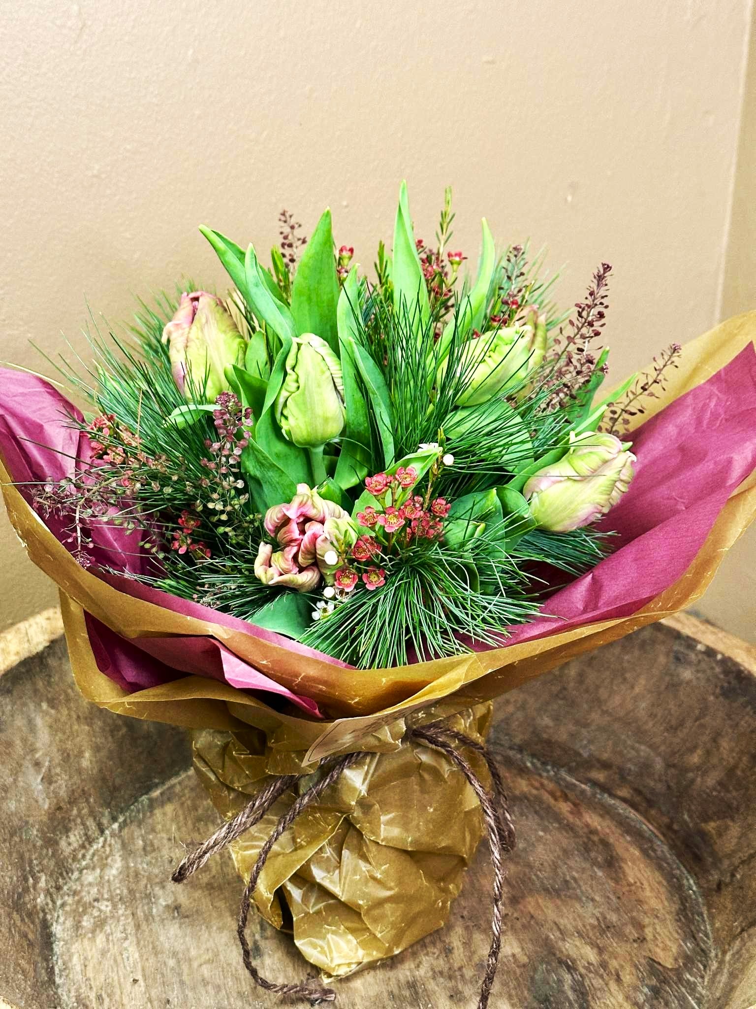 Tulipanbuket i lyse farver, bundet med gran og blandet vintergrønt. 