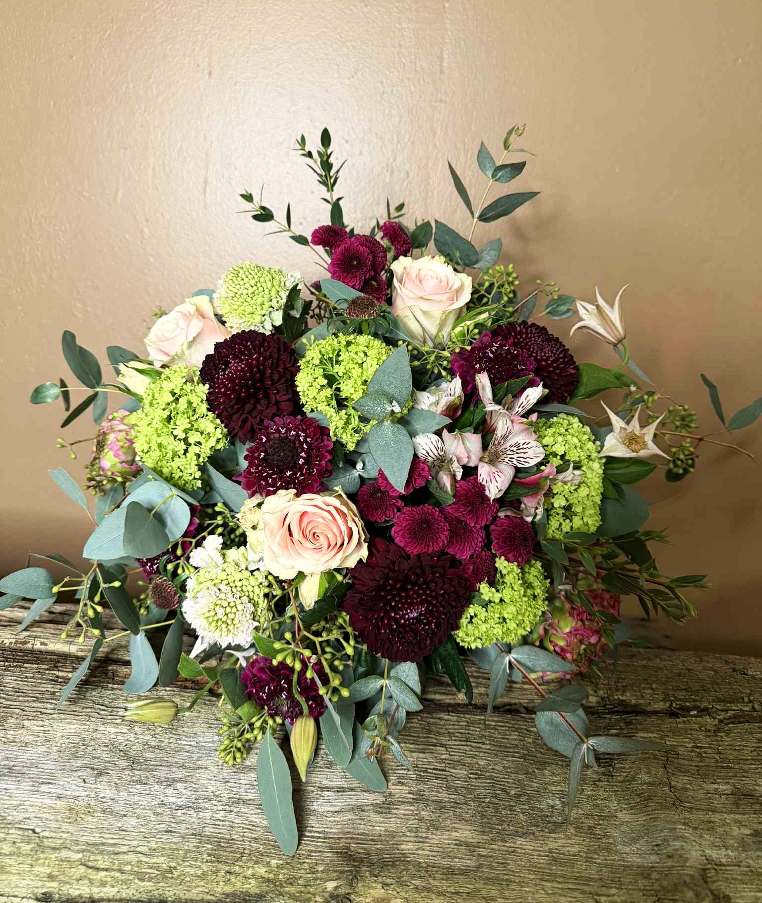 Romantisk og tæt buket med røde roser, amaryllis og blomster i rosa farver. 