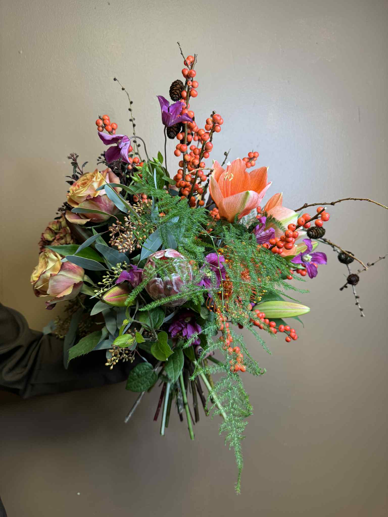 Floras Kreative Sæson buket bundet med amaryllis, roser, bærgrene og årstidens blomster. 