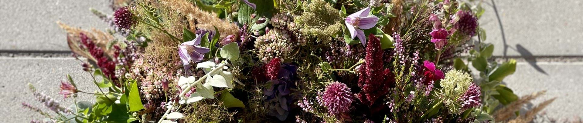 Krans bundet af forskellige blomster i lilla og bordeaux nuancer