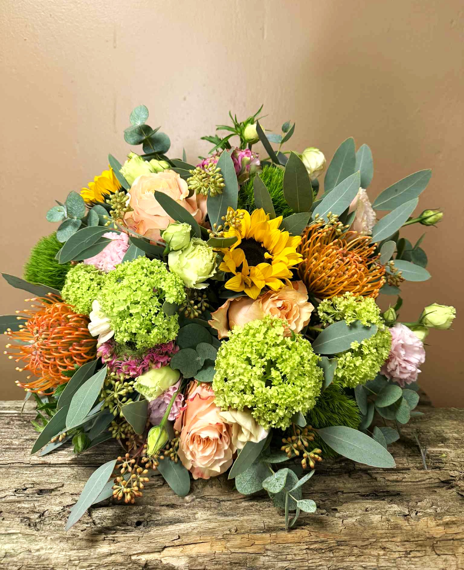 Farverig blomsterbuket Floras Passion med gule, ferskenfarvede og grønne nuancer, håndbundet med sæsonens blomster