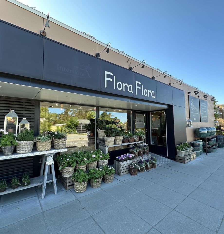 Flora Flora's butiksfacade med opsatte planter og dekorationer.  