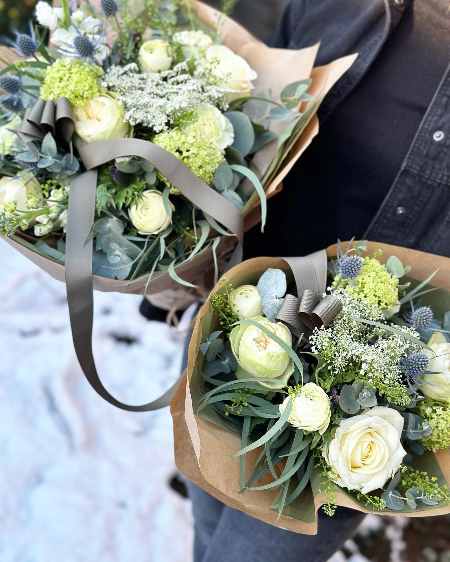 To smukke buketter til den nye mor og den nyfødte baby. Buketterne er pakket i brunt papir og blomster i lyse farver. 