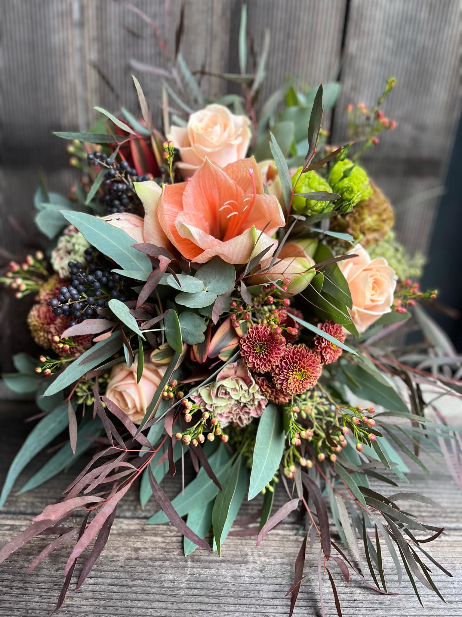 Buketten "Floras magi" med amaryllis og blomster i grønne og orange farver. 