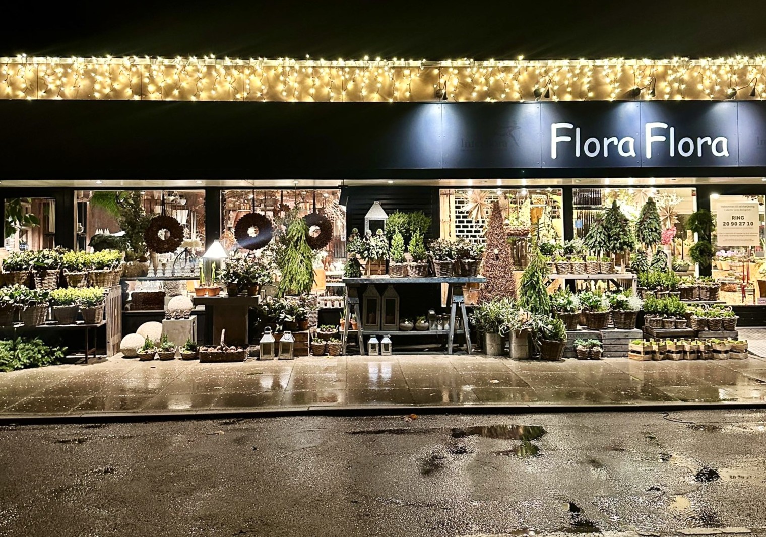 Facaden af butikken Flora Flora, er pyntet op til jul. Der funkende julelys i gavlen og på gaden, vintergrønt i krukker og kurve. 