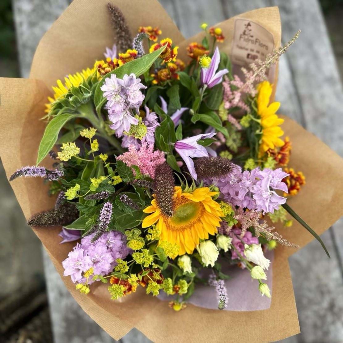 Floras sensommer med skarpe gule solsikker, lilla, grønne og rosa farvede blomster.